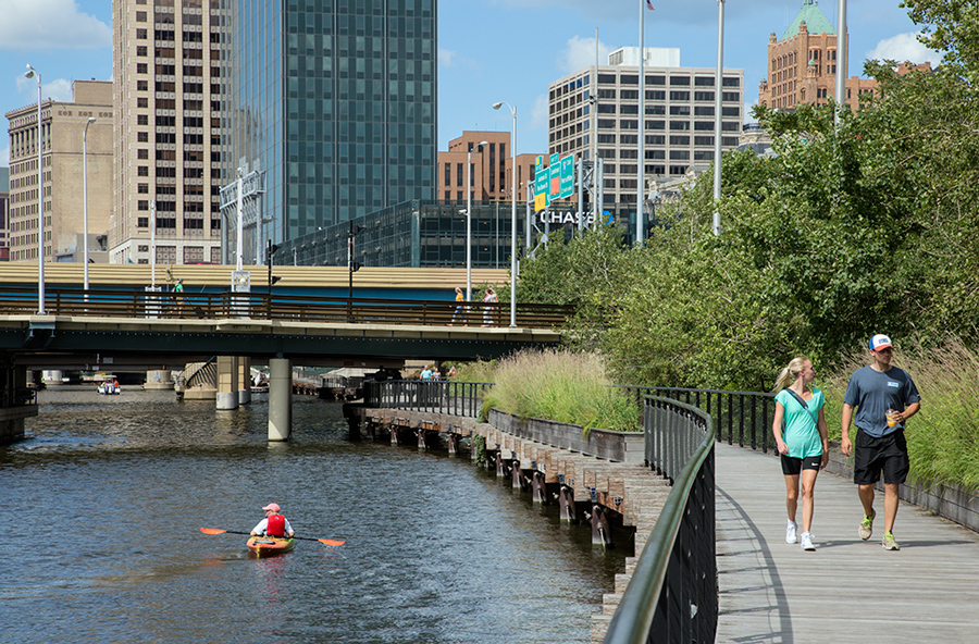 kayak on river and walkers on Milwaukee River Riverwalk