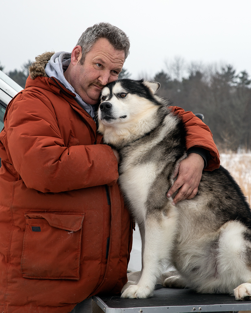 Owner Mark Reisner cuddling sled dog