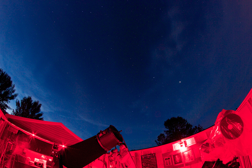 The telescope and night sky from inside the observatory