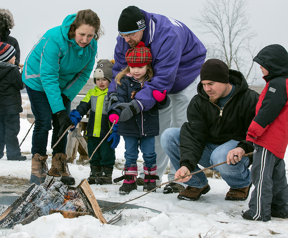 family roasting marsmallows over an outdoor fire