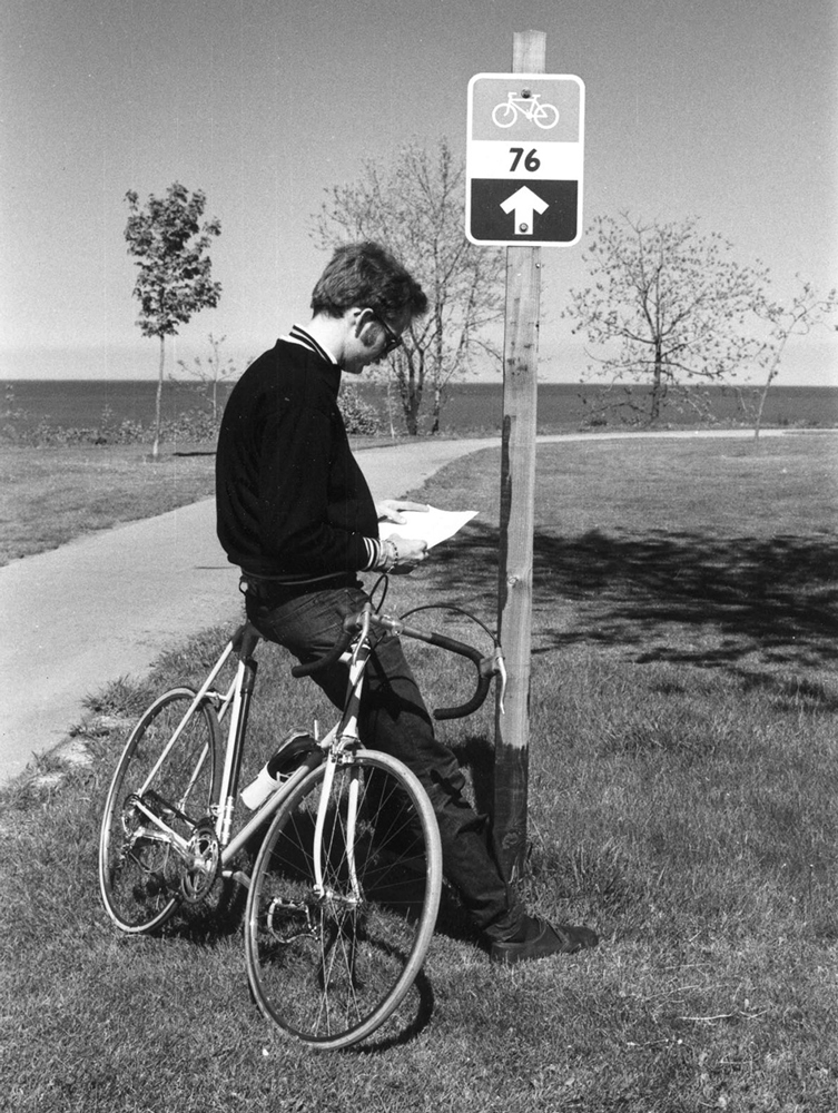 man leaning on bike reading