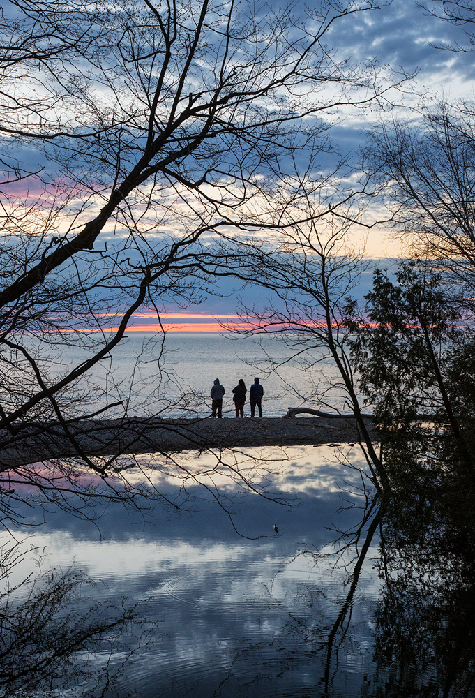 Three people on Lake Michign beach at sunrise