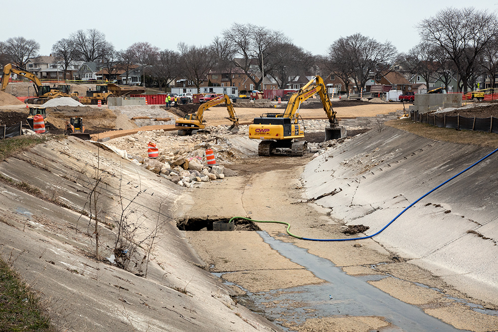 construction vehicles removing concrete channel from riverbed