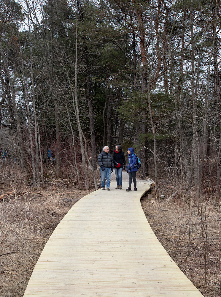 three people walking along a boardwalk