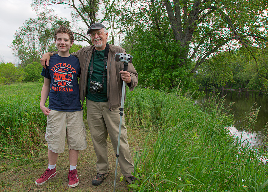 Artist in residence Hal Rammel and camera with a teenage boy next to Milwaukee River