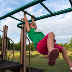 a girl swinging on a playground structure