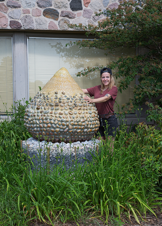 The artist, a young woman, with her tear-drop shaped sculpture, entitled Geo Egg