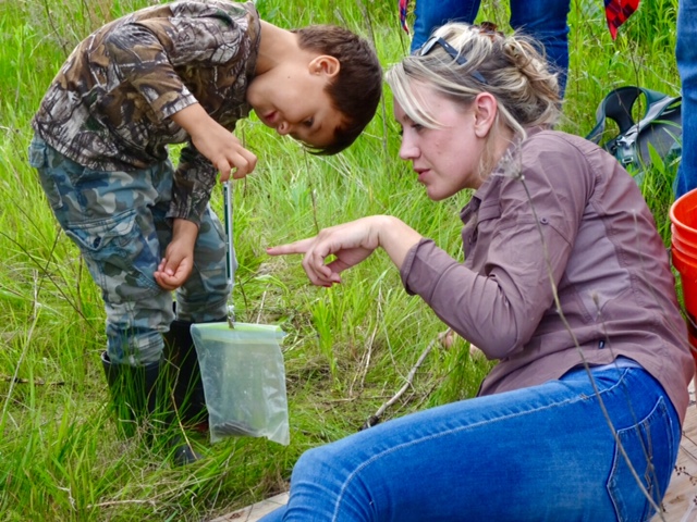 Julia Robson assists a young scientist in determining the mass of a snake.