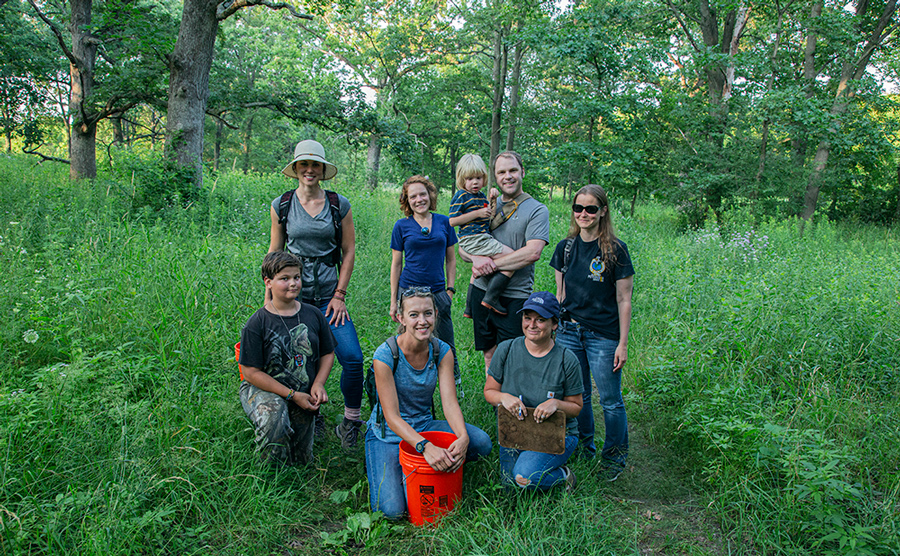 six adults and two children citizen scientists on a trail in a woodland