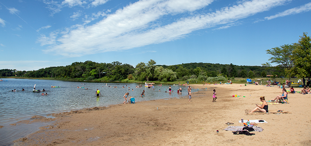 sandy beach at a lake with people sitting and bathing