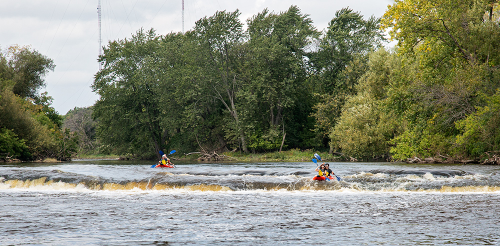 panoramic view of two red rubber rafts approaching the falls in Estabrook Park