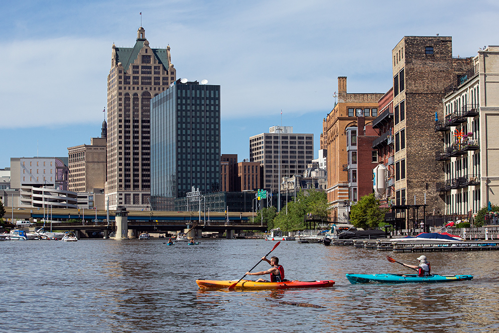 two kayaks on the Milwaukee River with downtown buildings in the background