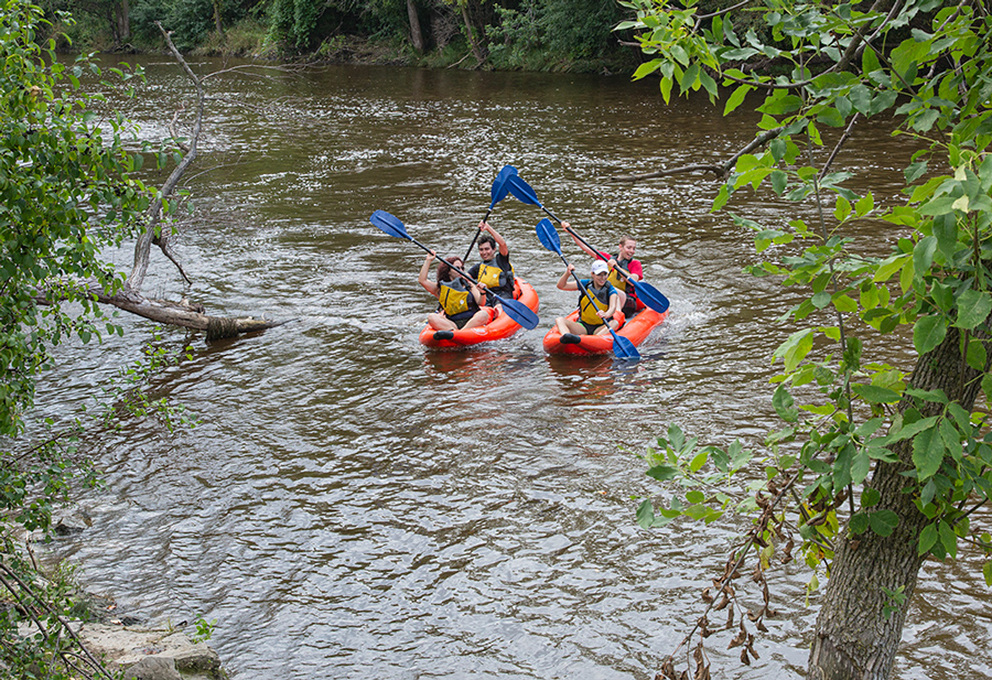 Two red rubber rafts paddling toward shore on the Milwaukee River