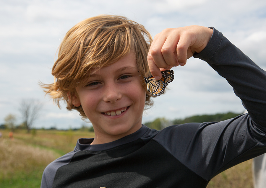 a boy holding a monarch butterfly by the wings