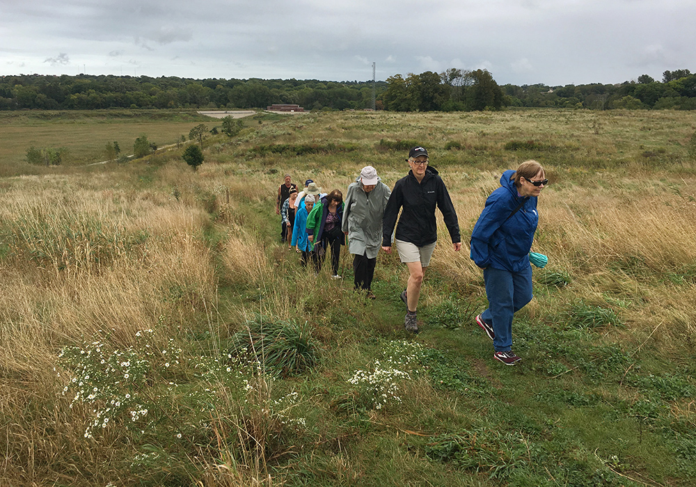 a group of hikers walking up a hillside in a prairie at County Grounds Park in Wauwatosa