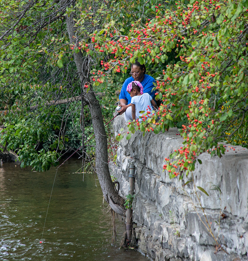 mother and child fishing from a wall