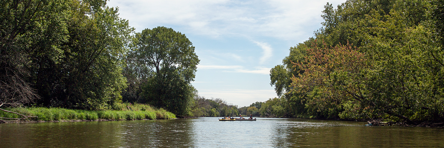 a canoe and rafts floating in the middle of a wide river