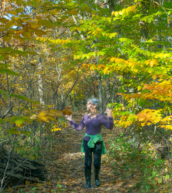 a woman expressing joy at being in the beautiful autumn woods