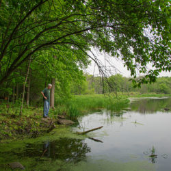 a man standing on the shore of the Ocomomowoc River