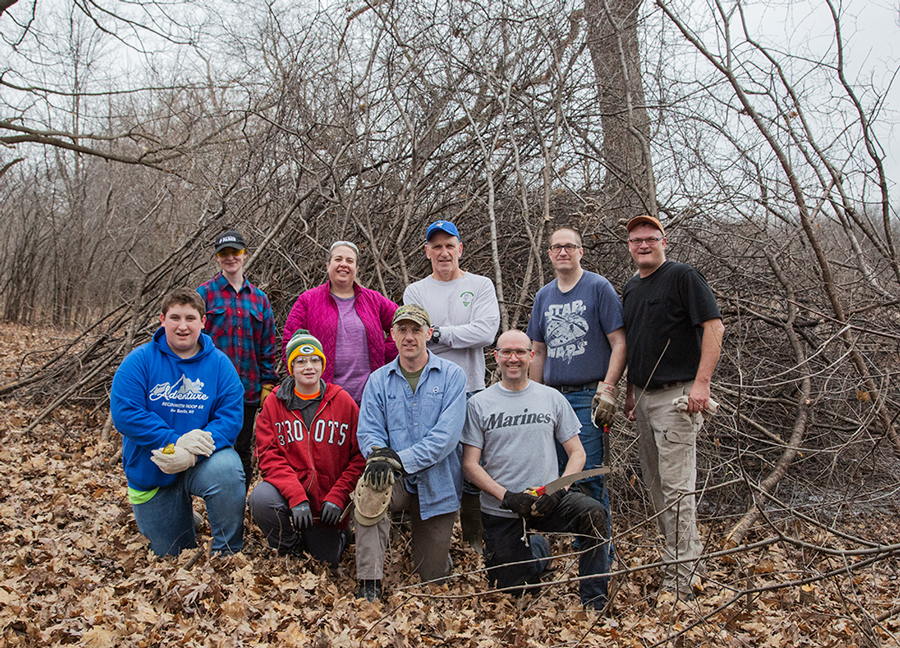 Buckthorn brigade volunteers with a pile of cleared buckthorn