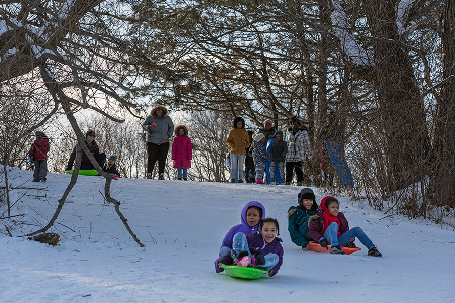 people watching as two sleds go down the hill