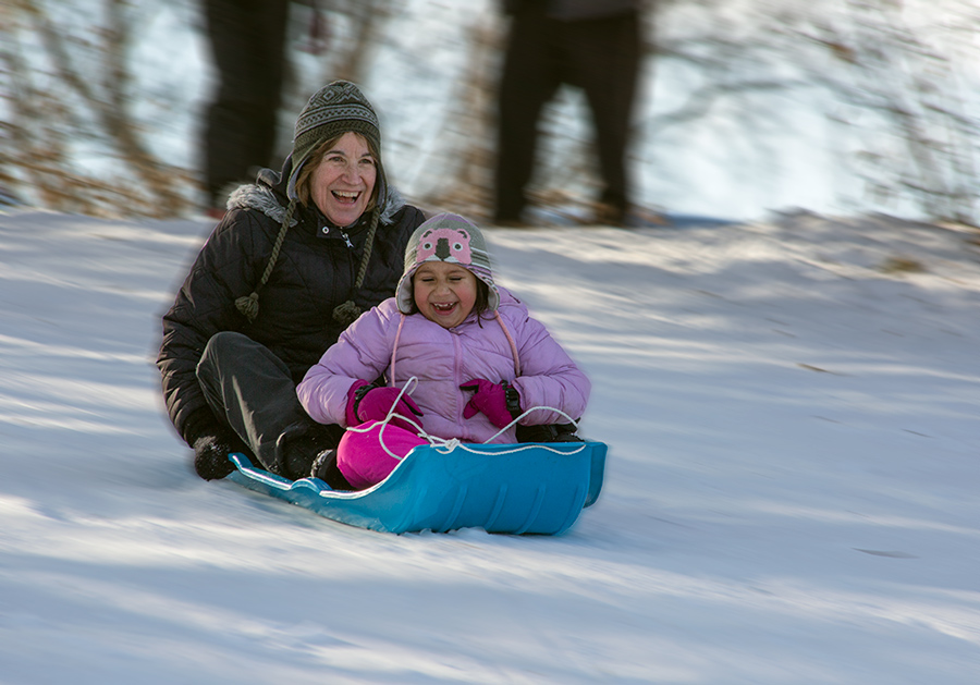 An adult and child sledding together