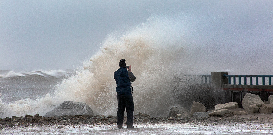 Man with iPhone facing the surging surf on Milwaukee's lakefront