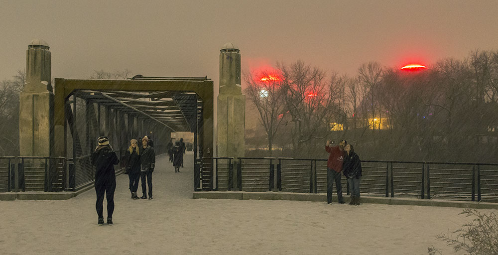 People taking selfies in Three Bridges Park during Urban Candlelight Hike, with the Domes in the background