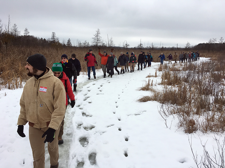 A line of hikers walking on the frozen stream