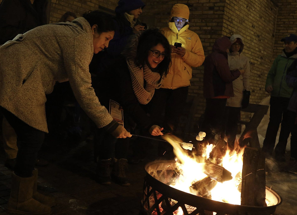 Two young women roasting marshmallows.