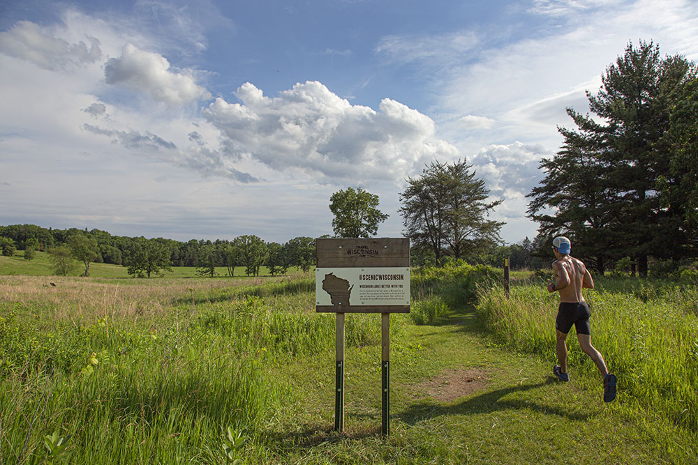 A man jogging on a trail in an open field at Lapham Peak