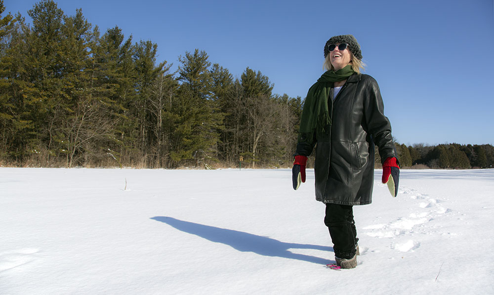 A woman walking in an open, snowy field at Schoofs Preserve