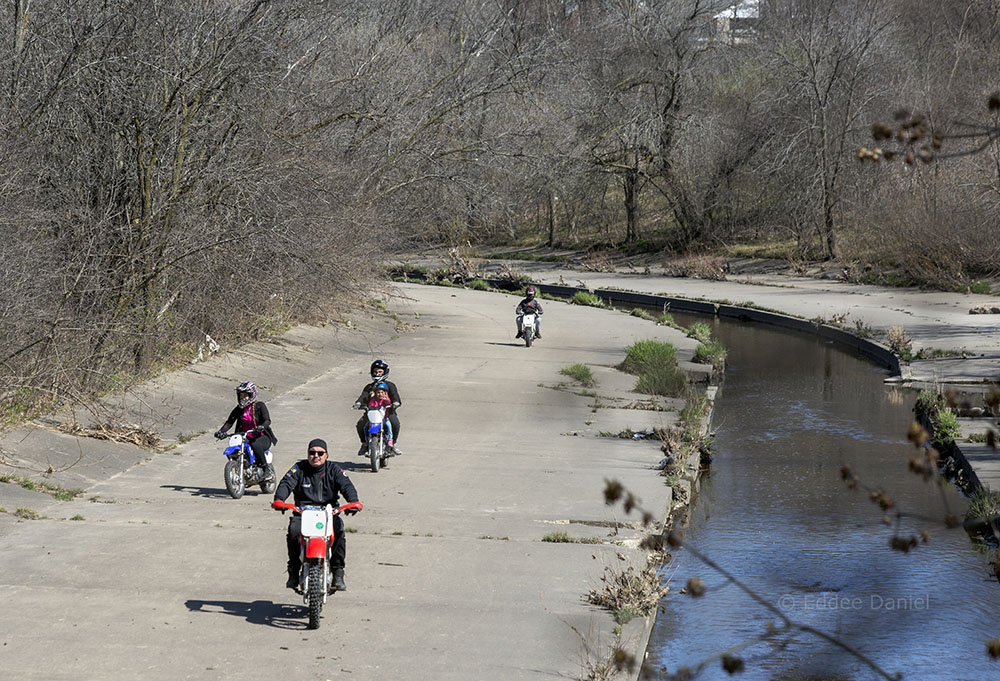 A family of motorbikes using the Kinnickinnic River as a race course.