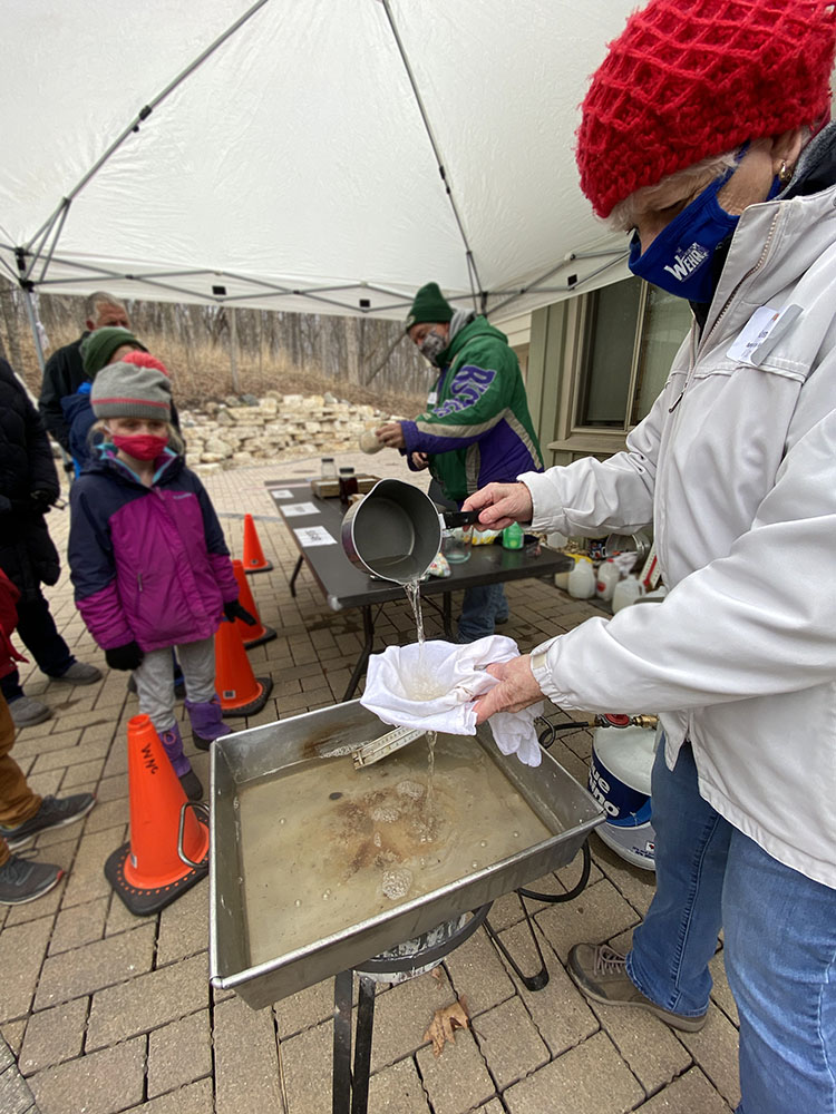 Volunteer Karen Kerans demonstrating how to filter the sap for boiling.