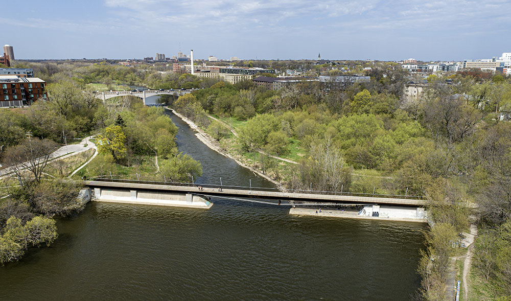 Former dam site with pedestrian bridge over remaining dam abutments. 