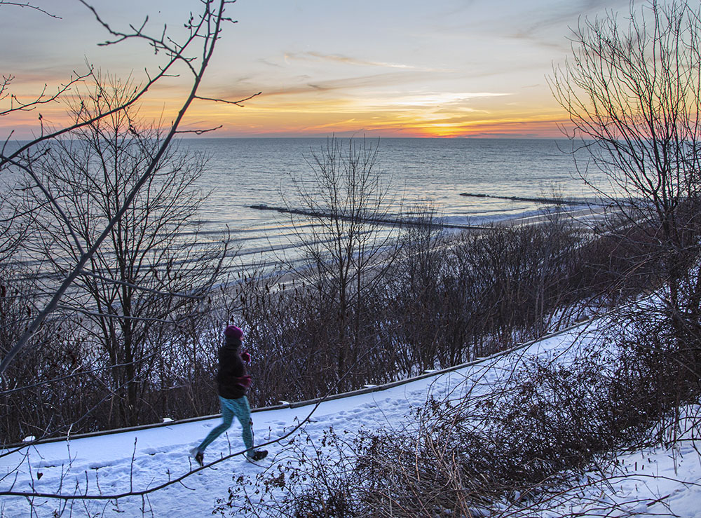 Sunrise over Lake Michigan creates a colorful backdrop for this jogger at Atwater Park in Shorewood.