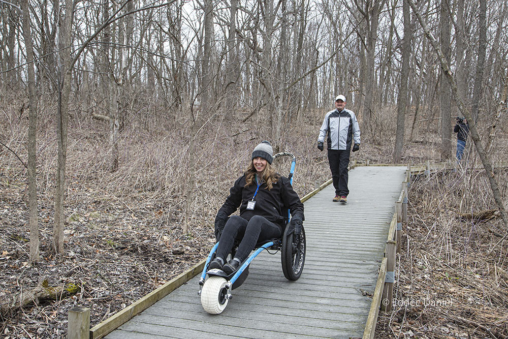 Wehr Nature Center Director Carly Hintz tries out one of the wheelchairs, followed by Parks Director Guy Smith.