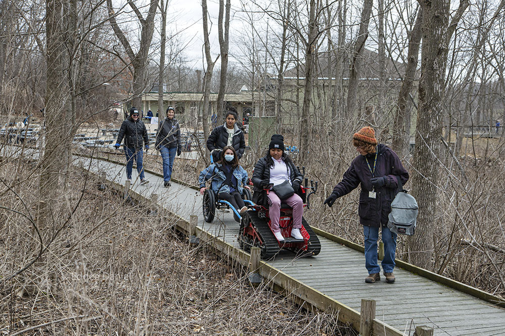 Karen, a volunteer, leads a guided hike along the boardwalk outside the Center (background).