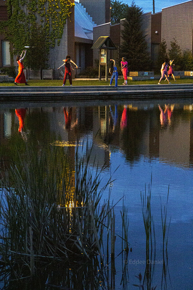 dancers at the edge of the lagoon in front of the Urban Ecology Center