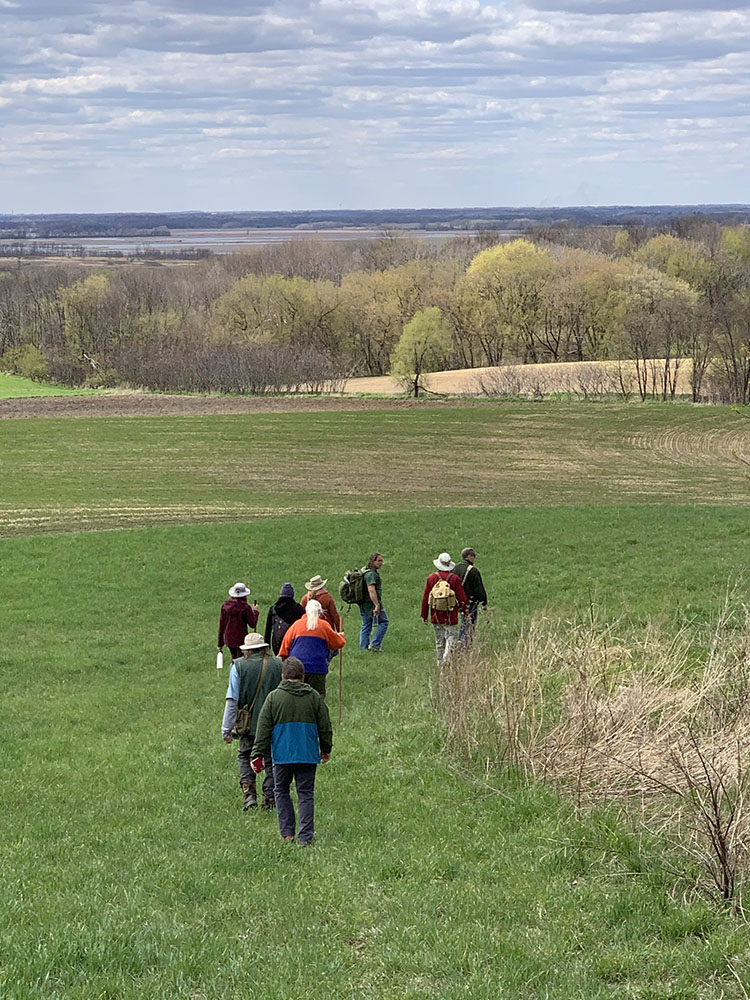 The group walks across a field toward the Kolterman mounds, with Horicon Marsh in the distance.