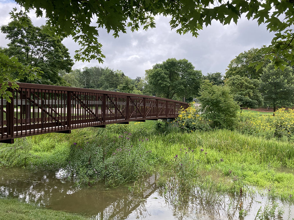 The footbridge, here over a swollen creek after a morning of rain, leads to Indian Creek Park.