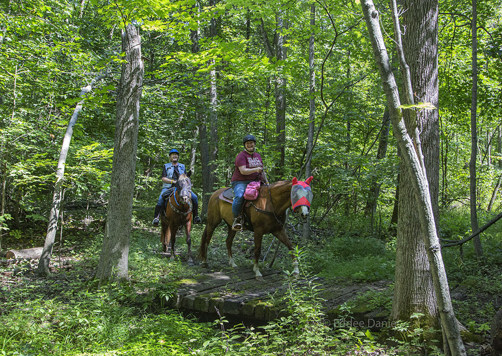 A pair of joyful riders cross a bridge on the Short Road Trail.