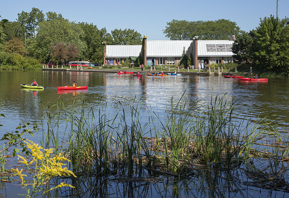 Beginner class of kayakers in the lagoon in front of the Urban Ecology Center.