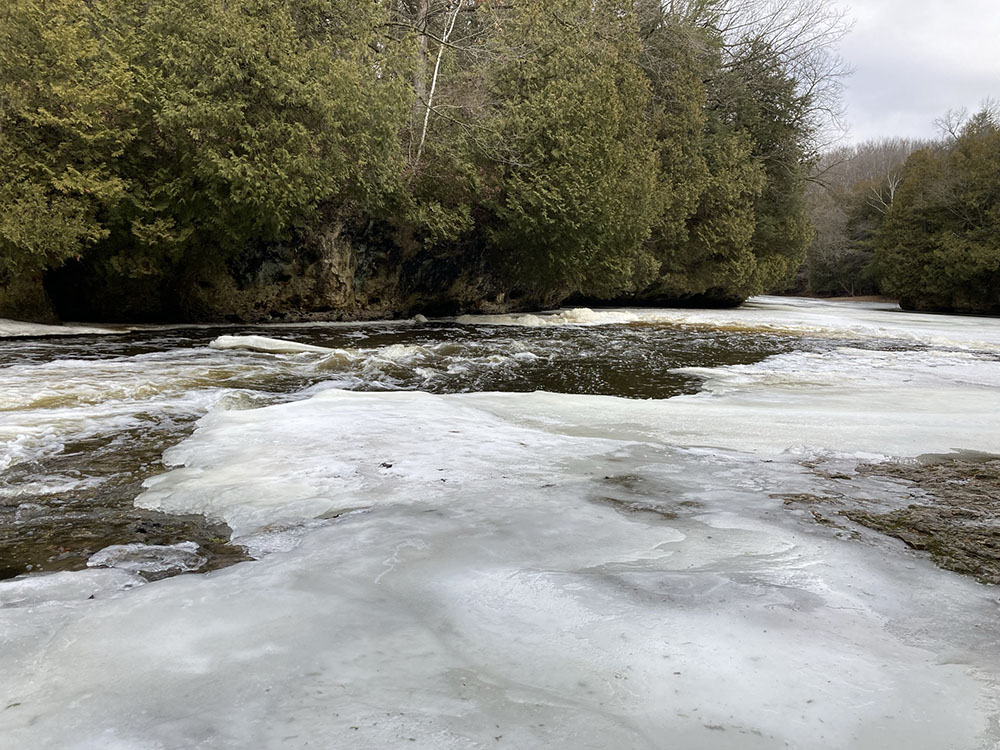 Below the cascades, the river flows past tall rock outcroppings.