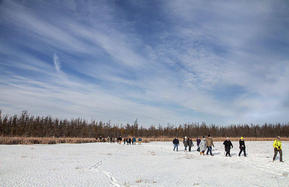 The hike reaches frozen Long Lake, spreads out across its surface.