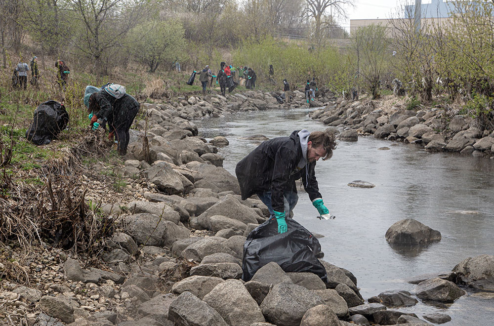 Crowds of volunteers help clean up the Kinnickinnic River near Sixth Street in the midst of a snow squall.