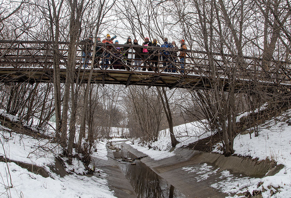 The group gathered on the pedestrian bridge over the channelized creek near its confluence with Lincoln Creek.