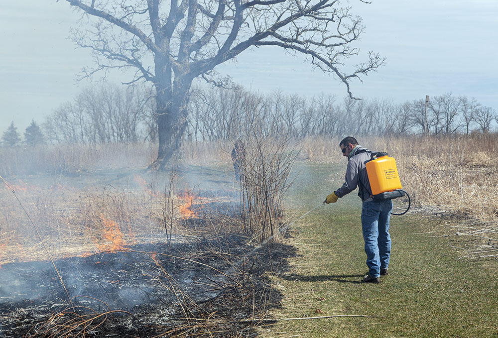 A team member douses hot spots with water to tamp down the blaze.