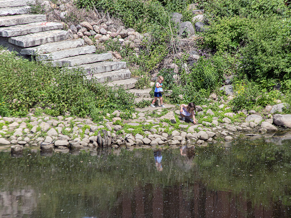 Two young children take a break from the festivities to explore the bank of the Menomonee River.