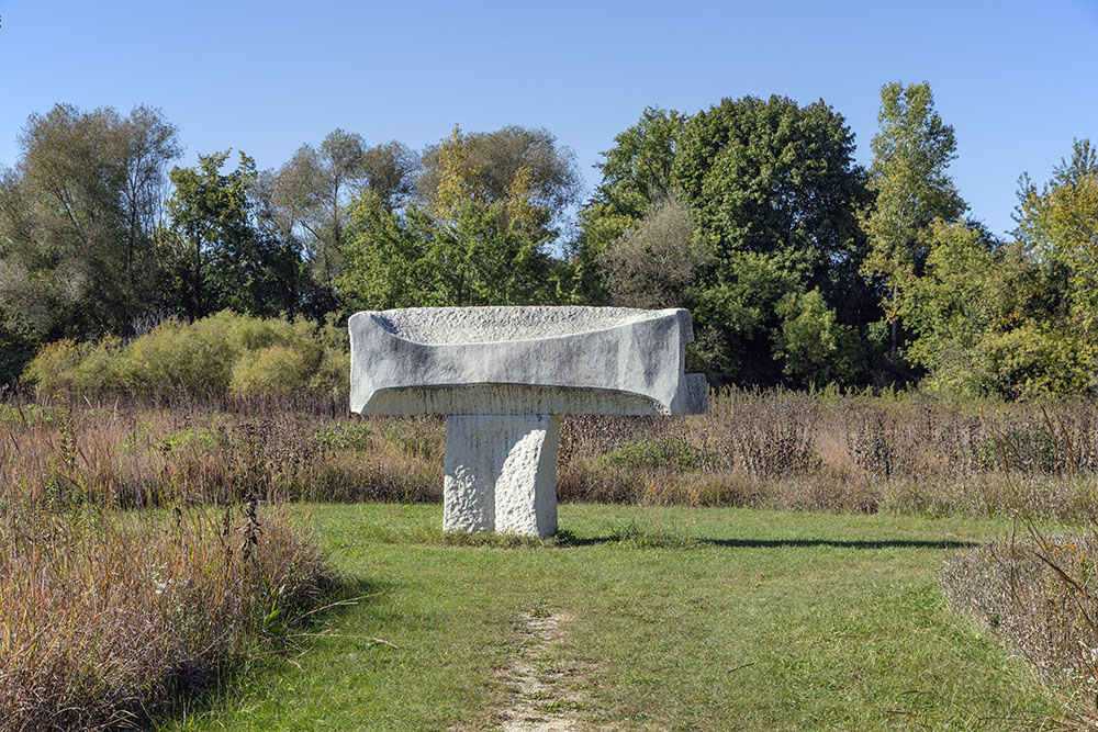 "Fluvio" by Paul Trappe (Australia). Made from 24,000 lbs. of limestone, which appears to levitate above the prairie plants. "Fluvio" is Italian for "of the river." It is located next to the Menomonee River in Riverfront Parkway.